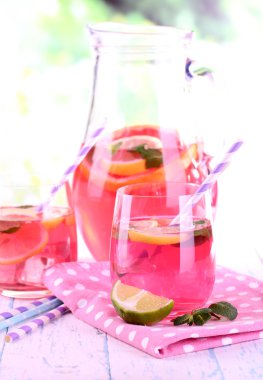 Gözlük ve sürahi doğal zemin üzerine masada pembe limonata