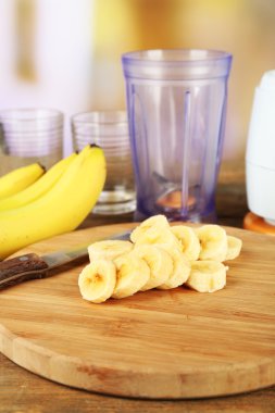 Parlak zemin üzerine ahşap masa üzerinde kesme tahtası üzerinde muz dilimlenmiş