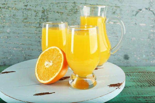 Vaso de zumo de naranja con rodajas sobre fondo de madera de color — Foto de Stock