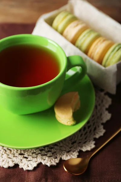 Macaroni colorati con tazza di tè su sfondo di legno — Foto Stock