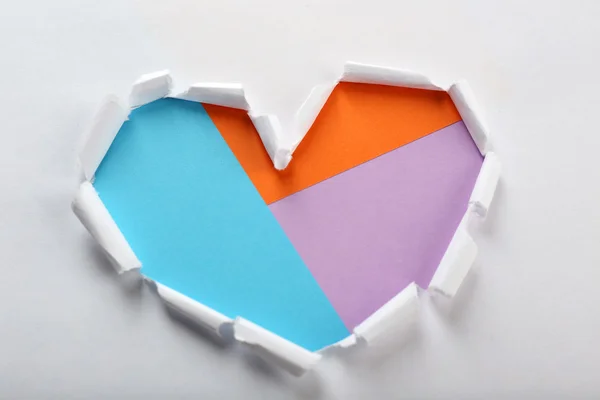 Renkli arka plan üzerinde beyaz yırtık kağıt kalp — Stok fotoğraf