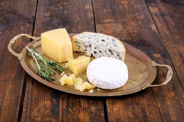 Different types of cheese on metal tray and wooden table background — Stock Photo, Image