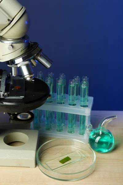 Microscope and test tubes on table, on color background — Stock Photo, Image