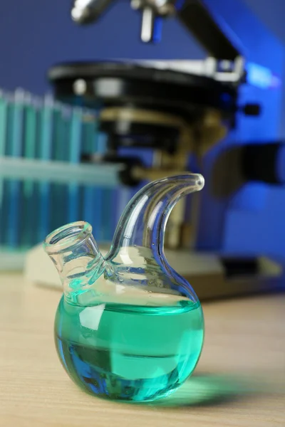 Microscope and test tubes on table, on color background — Stock Photo, Image