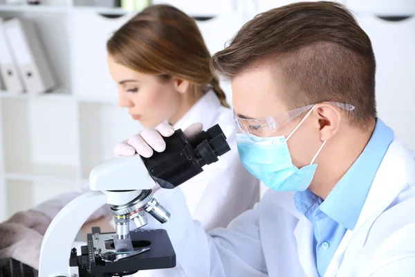 Giovani scienziati di sesso femminile e maschile con microscopio in laboratorio — Foto Stock