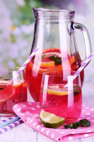 Rosa Limonade in Gläsern und Krug auf dem Tisch vor natürlichem Hintergrund — Stockfoto