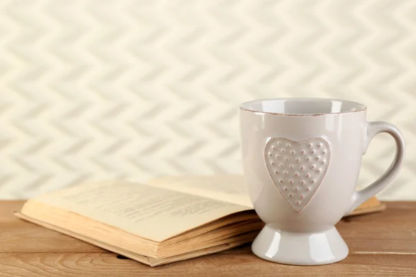 Taza de té y libro sobre la mesa, sobre fondo claro — Foto de Stock