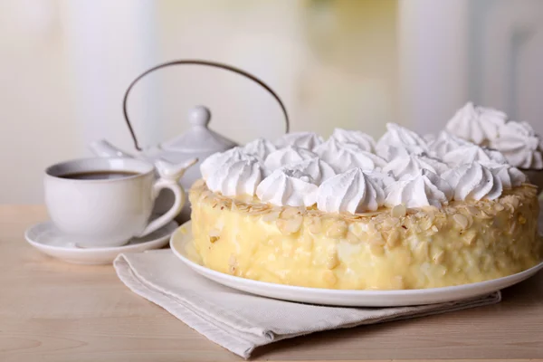 Smakelijk zelfgemaakte meringue taart en kopje thee op houten tafel, op lichte achtergrond — Stockfoto