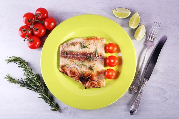 Dish of Pangasius fillet with rosemary and cherry tomatoes in plate on color wooden table background — Stock Photo, Image