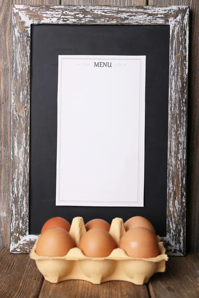 Tablero de menú con huevos sobre tablones de madera rústica fondo — Foto de Stock