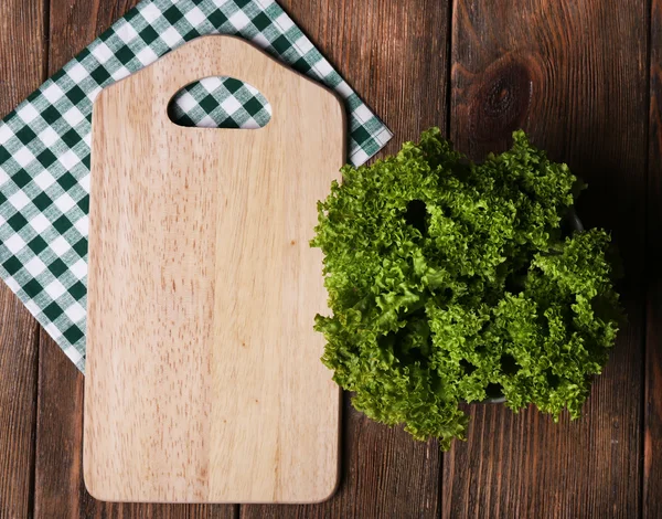 Cutting board with lettuce on wooden planks background — Stock Photo, Image