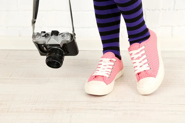 Meisje in sneakers met retro fotocamera op kamer — Stockfoto