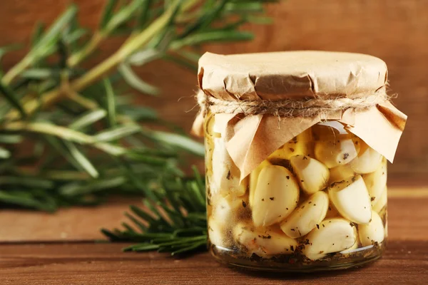 Canned garlic in glass jar on wooden background — Stock Photo, Image