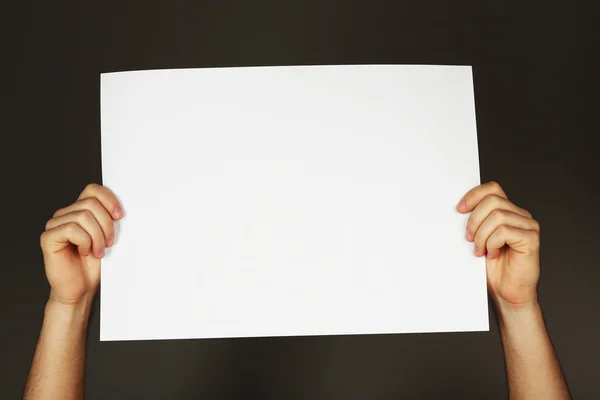 Hoja de papel en blanco en manos masculinas sobre fondo oscuro —  Fotos de Stock