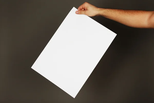 Blank sheet of paper in male hand on dark background — Stock Photo, Image