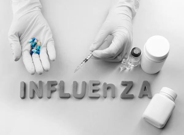 Mano humana de píldoras Medicamentos con palabra Influenza sobre fondo claro — Foto de Stock