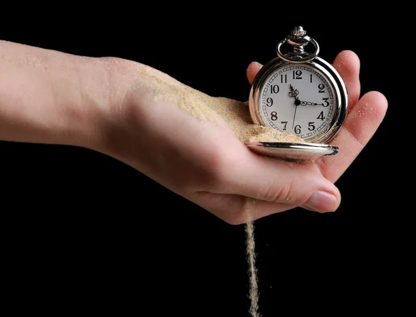 Silver pocket clock in hands and sand flowing away on black background — Stock Photo, Image