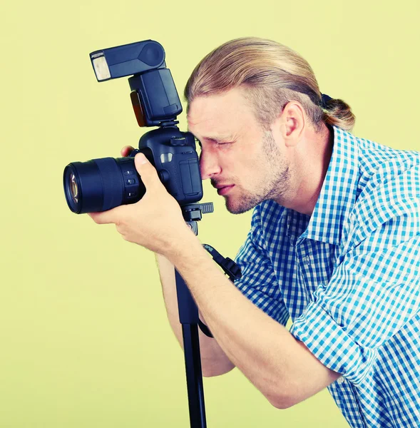 Bello fotografo con macchina fotografica su monopiede, su sfondo verde — Foto Stock