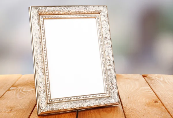 Photo frame on wooden table on bright background — Stock Photo, Image