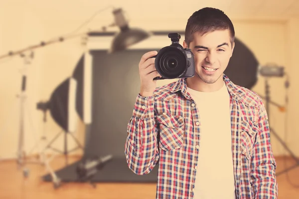 Handsome photographer with camera in photo studio