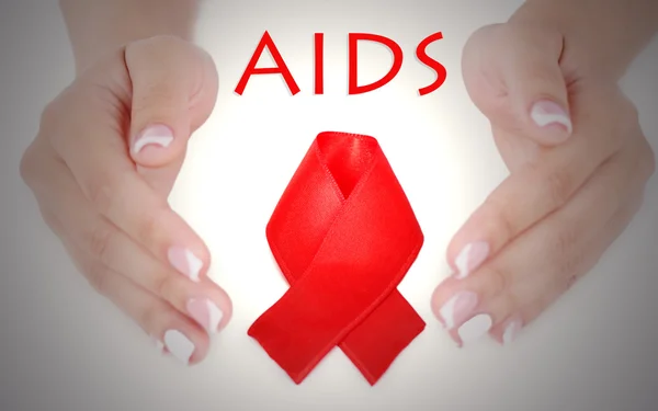 Woman with aids awareness red ribbon in hands — Stock Photo, Image