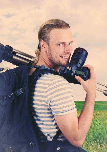 Young photographer with camera and tripod on nature background — Stock Photo, Image