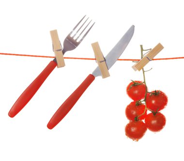 Çatal, bıçak ve beyaz arka plan üzerinde izole clothesline asılı olgun kırmızı domates
