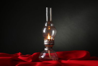 Koyu arka plan üzerinde kırmızı kumaş üzerine gaz lambası