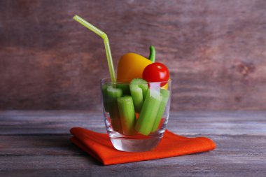 Kereviz tatlı biber ve kiraz domates cam tüp ve rustik ahşap zemin üzerine peçete ile sopa