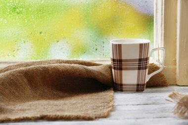 Yağmur arka plan pencere kenarında üzerinde çul ile sıcak içecek fincan