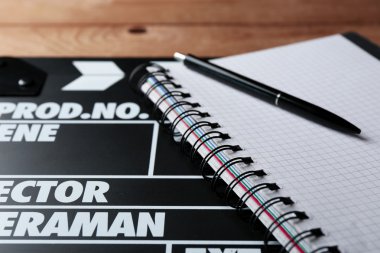 Film tokmağı ile defter ve kalem ahşap arka plan üzerinde