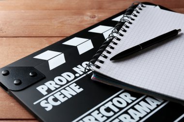 Film tokmağı ile defter ve kalem ahşap arka plan üzerinde