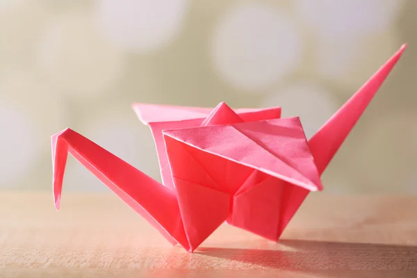 Origami crane on wooden table, on light background — Stock Photo, Image