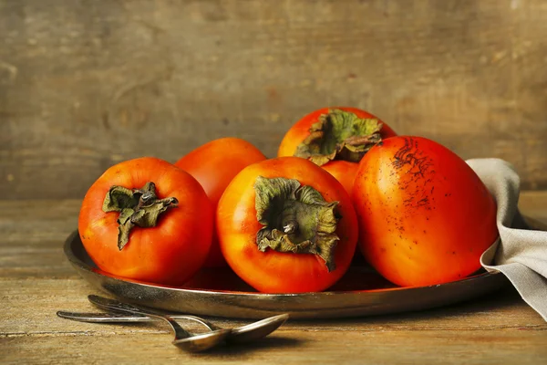 Ripe sweet persimmons, on wooden table — Stock Photo, Image