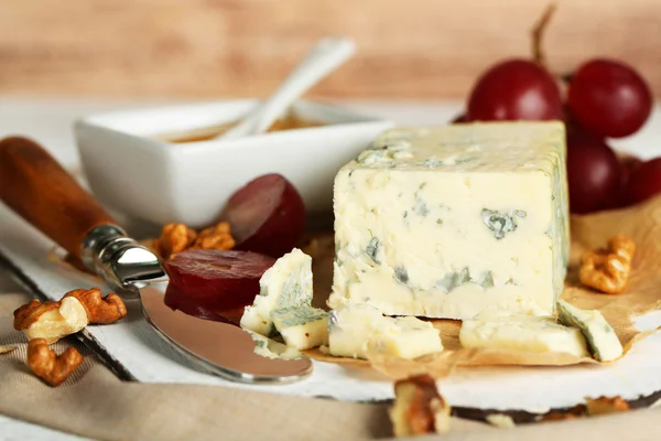 Stilleven met smakelijke blauwe kaas op tafel, op houten achtergrond — Stockfoto