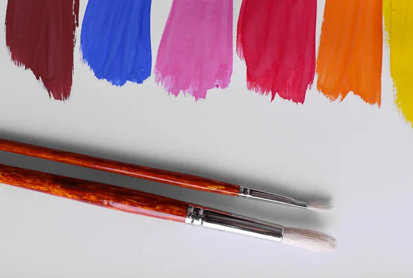 Colorful paint strokes with brush on white sheet of paper background — Stock Photo, Image