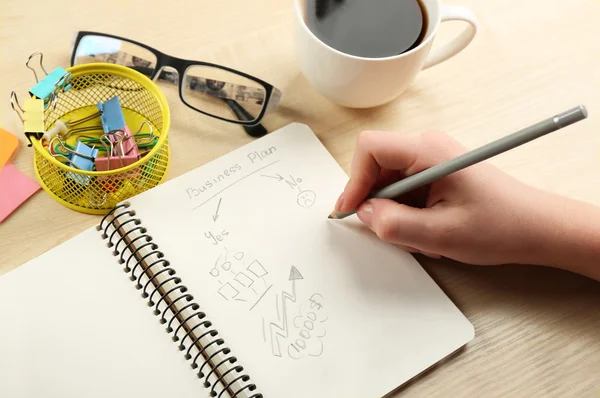 Weibliche Handschrift am Notizbuch mit Tasse Kaffee am Holzschreibtisch Hintergrund — Stockfoto
