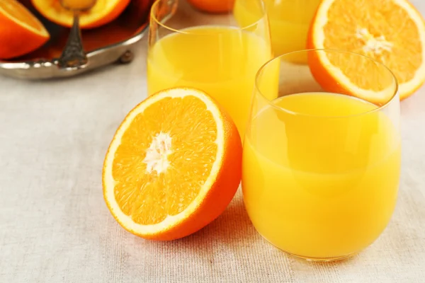 Copo de suco de laranja com fatias em fundo de toalha de mesa — Fotografia de Stock