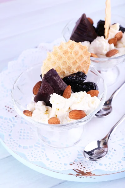 Postre con ciruelas pasas en cuencos de vidrio sobre fondo de mesa de madera de color — Foto de Stock