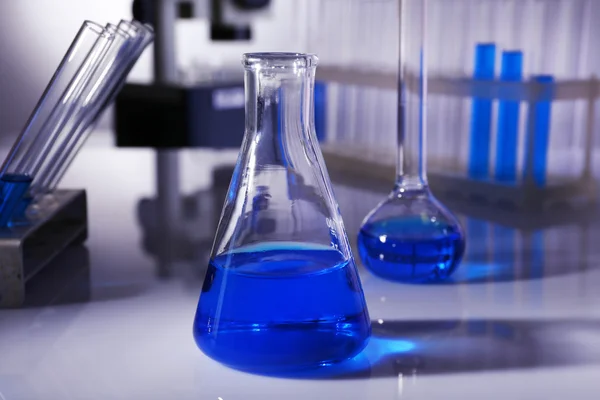 Verrerie de laboratoire avec liquide bleu sur fond gris — Photo