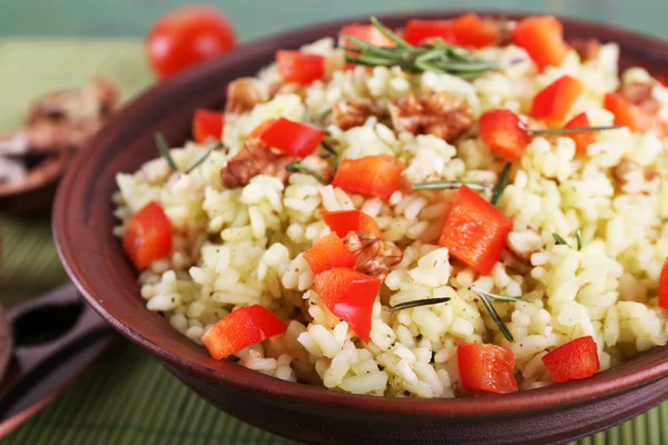 Rijst met walnoten en cherry tomaten in plaat op bamboe mat achtergrond — Stockfoto