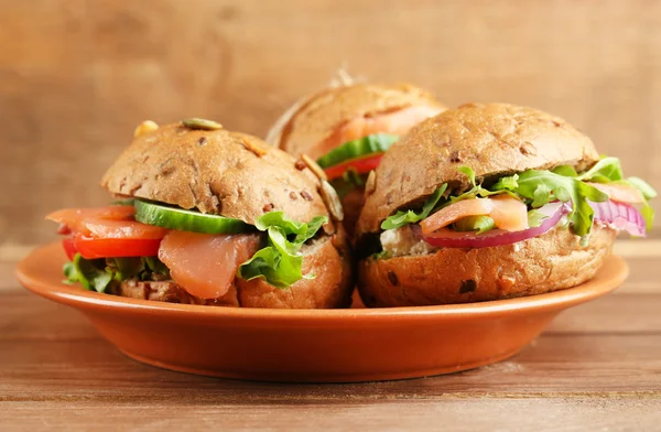 Sandwiches with salmon on plate, on wooden background — Stock Photo, Image