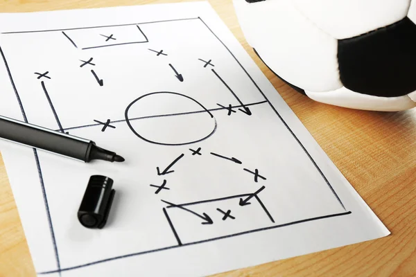 Схема футбольної гри на аркуші паперу та дерев'яному фоні столу — стокове фото