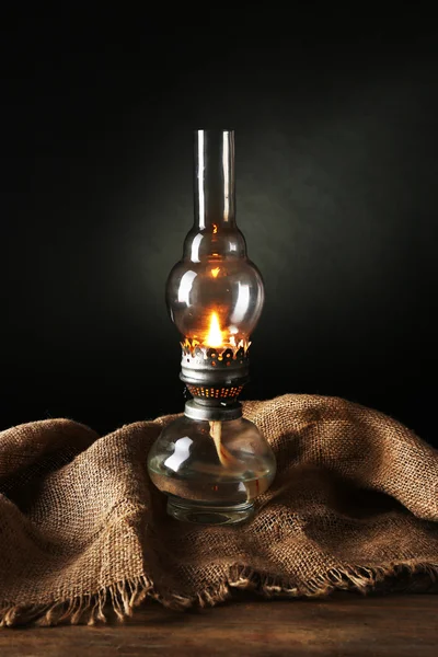 Kerosene lamp with burlap cloth on dark background — Stock Photo, Image