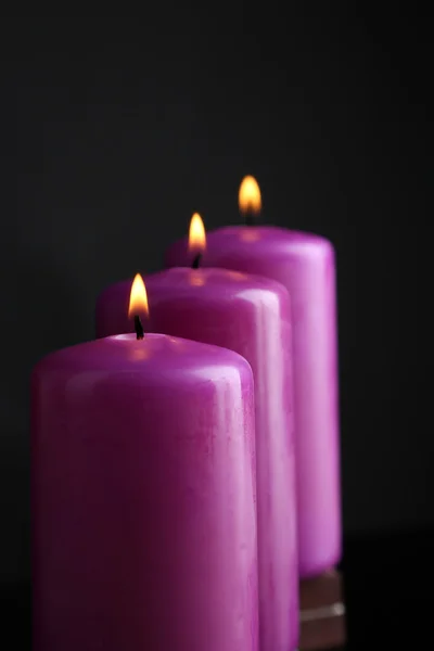 Fioletowe świece na czarnym tle — Zdjęcie stockowe