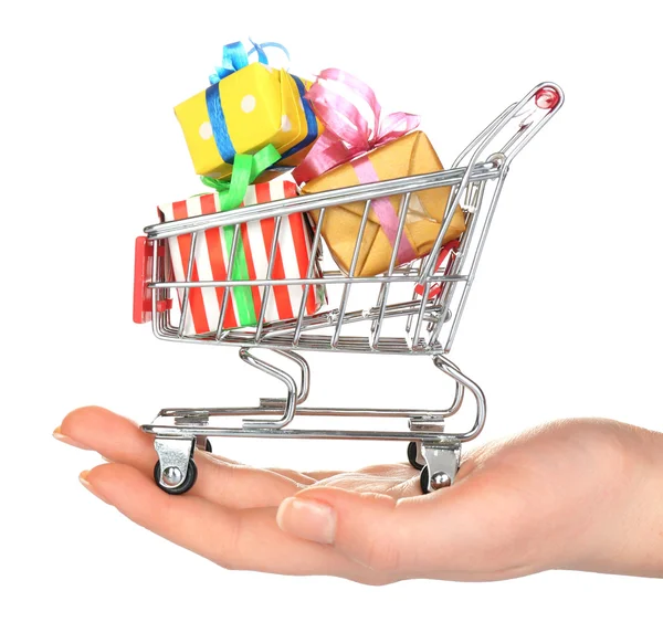 Mano femenina con carrito de compras pequeño lleno de regalos, aislado en blanco — Foto de Stock