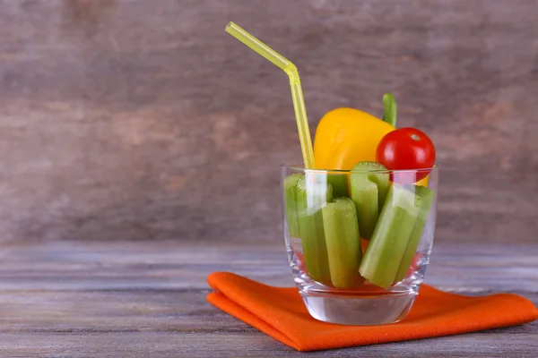 Stokken van selderij met paprika en cherry tomaat in glas met buis en servet op rustieke houten achtergrond — Stockfoto