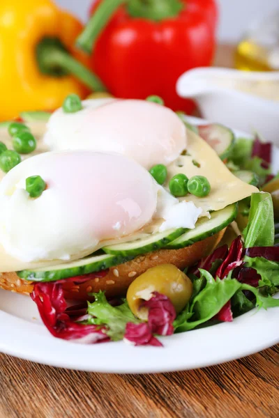 Sandwich mit pochierten Eiern, Käse und Gemüse auf Teller auf Holzgrund — Stockfoto