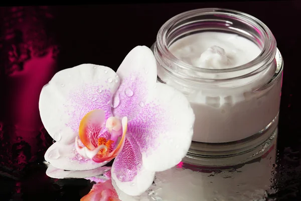 Face cream with orchid flower on dark background — Stock Photo, Image