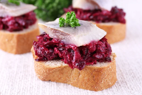 Rye toasts with herring and beets on tablecloth background — Stock Photo, Image